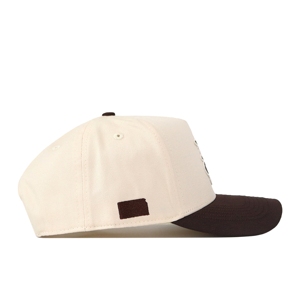 The Wichita State Espresso Hat by No Rivals is a cream-colored snapback with a dark brown brim and a small rectangular brown patch near the back, made from high quality cotton.