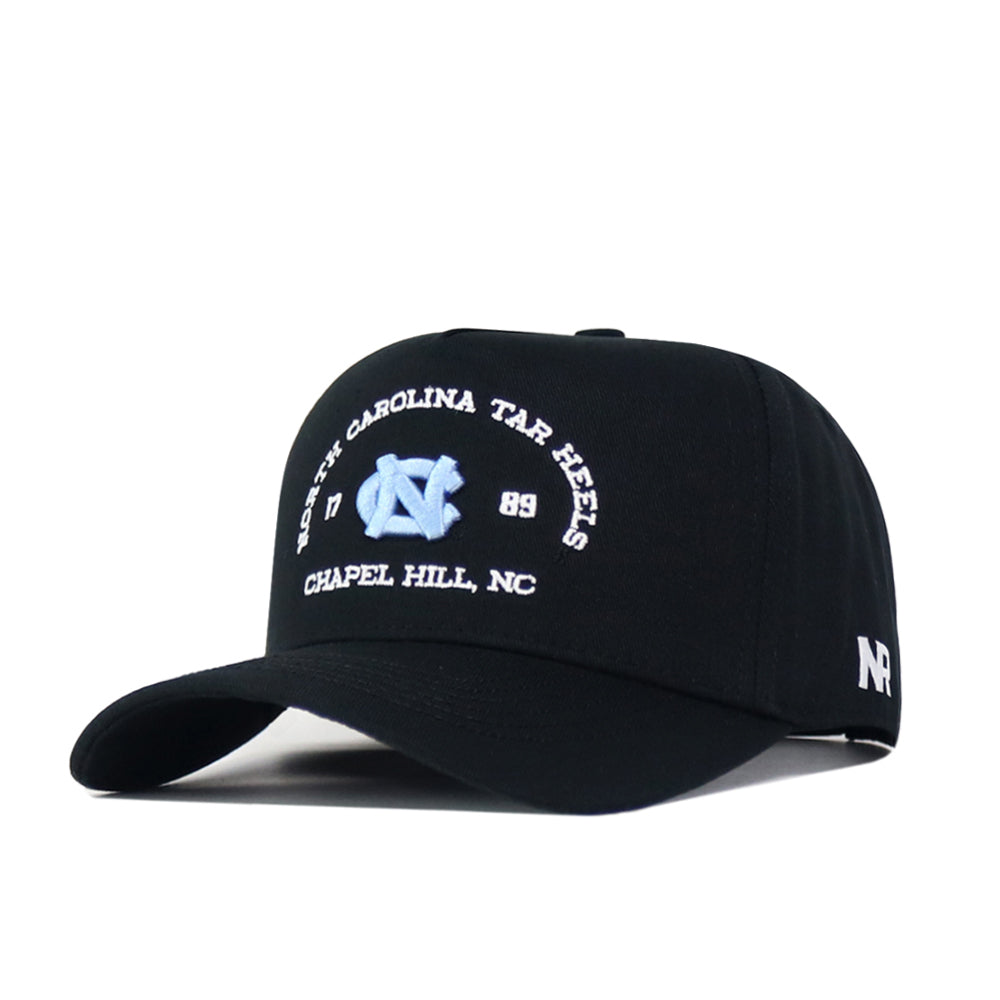 The UNC Outlaw Hat – Black by No Rivals features a structured fit and showcases the North Carolina Tar Heels, 1789, and Chapel Hill, NC, with a light blue embroidered logo on the front. The side displays a white “NR” embroidery, and the snap back closure ensures adjustable comfort.