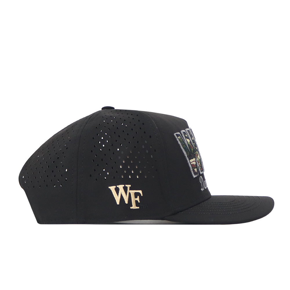 The Wake Forest Camo Block Hat by No Rivals is a black snapback featuring a gold WF logo on the side, perforated panels for ventilation, and a flat brim. The front showcases embroidered logos in white, green, and gold—perfect for elevating your gameday fit.