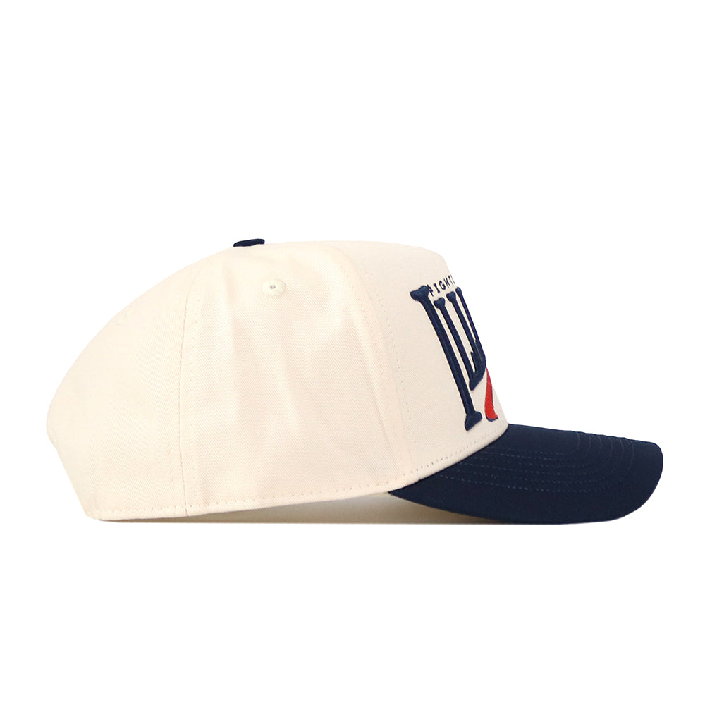 The Illinois Fighting Illini Stride Hat by No Rivals is a cream-colored snapback featuring a navy blue brim, shown here from the side. The front panel displays bold embroidered Illinois logos in navy and red—ideal for taking your gameday outfit to the next level.