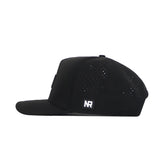 The Texas A&M Trainer Hat by No Rivals is a black snapback viewed from the side, featuring a structured fit, small ventilation holes on the crown, and a rectangular NR patch on the side.