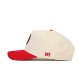 The No Rivals Utah Logo Patch Hat is a cream baseball cap with a red brim, seen from the side. "NR" in red 3D embroidery appears on the back side panel of this snapback.