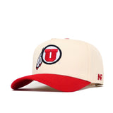 The Utah Logo Patch Hat by No Rivals is a cream snapback with a red brim, 3D embroidery of the University of Utah red U logo in a black circle with feathers, and "NR" stitched on the side. Officially licensed.
