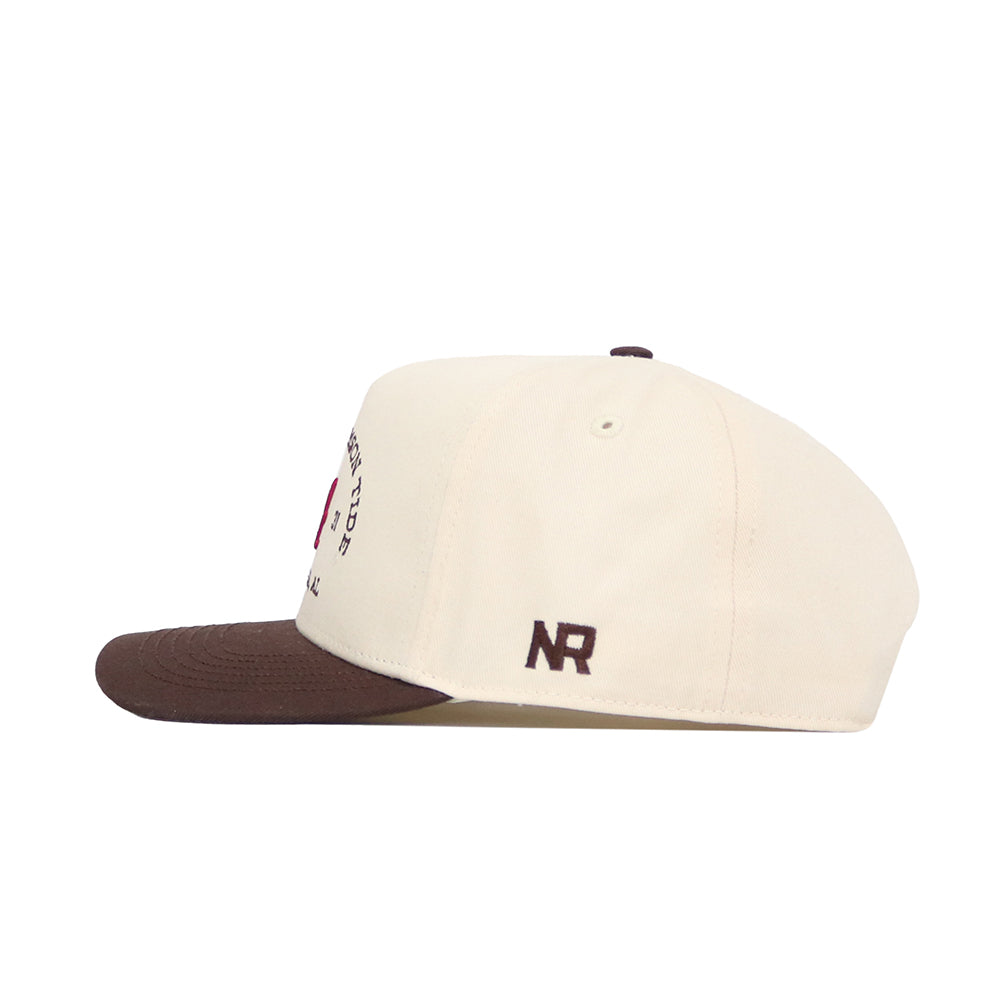 The No Rivals Alabama Outlaw Hat - Classic is a cream snapback with a brown brim, structured fit, and small dark brown NR logo embroidered near the back, crafted from high-quality cotton and shown in a side view.