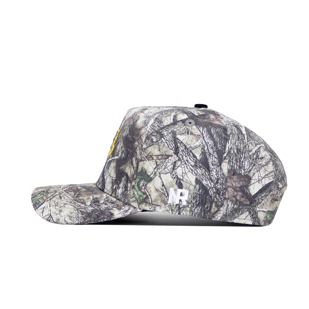 A side view of the No Rivals NDSU Outland Hat—a camouflage snapback with a flat brim, yellow logo on the front, white NB initials on the side, and a structured fit for style and comfort.