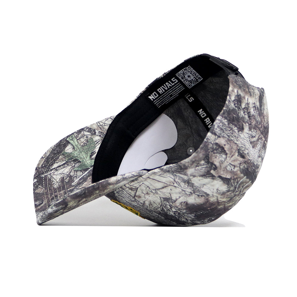 The NDSU Outland Hat by No Rivals is a camouflage snapback with a bent visor, white interior sticker, and a black inner band repeatedly printed with NO RIVALS. Made of high-quality cotton for comfort and durability.