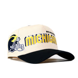 Show your Michigan spirit with the No Rivals Michigan Wolverines Alma Mater Hat—a cream and black snapback baseball cap featuring a bold yellow and blue football helmet graphic, prominent Michigan text on the front, and an embroidered logo. Perfect for your next game day look!.