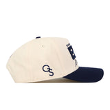 A Georgia Southern Erk Russell Hat by No Rivals, this beige baseball cap features a navy blue brim and an officially licensed embroidered "GS" logo in navy blue on the side.