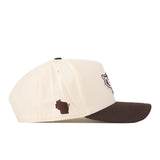 Introducing the No Rivals Wisconsin Badgers Espresso Hat—a snapback baseball cap in cream and brown, shown from the side. It features a brown embroidered outline of the state of Wisconsin on the cream front panel, adding a stylish finishing touch to your next gameday fit.