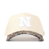 Introducing the Nebraska Camo Hat - Connector Edition by No Rivals: a high-quality cotton beige baseball cap with a white “N” on the front and a camouflage-patterned brim, displayed against a white background.