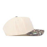 The Nebraska Camo Hat - Connector Edition by No Rivals is a beige baseball cap featuring a camouflage-patterned brim, crafted from high-quality cotton and displayed in a side view against a white background.