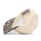 The Nebraska Camo Hat - Connector Edition by No Rivals is displayed upside down, revealing the inside label that reads “NO RIVALS” and a QR code on the inner bill. Crafted from high-quality cotton, this officially licensed snapback cap in beige and camouflage ensures lasting comfort and durability.