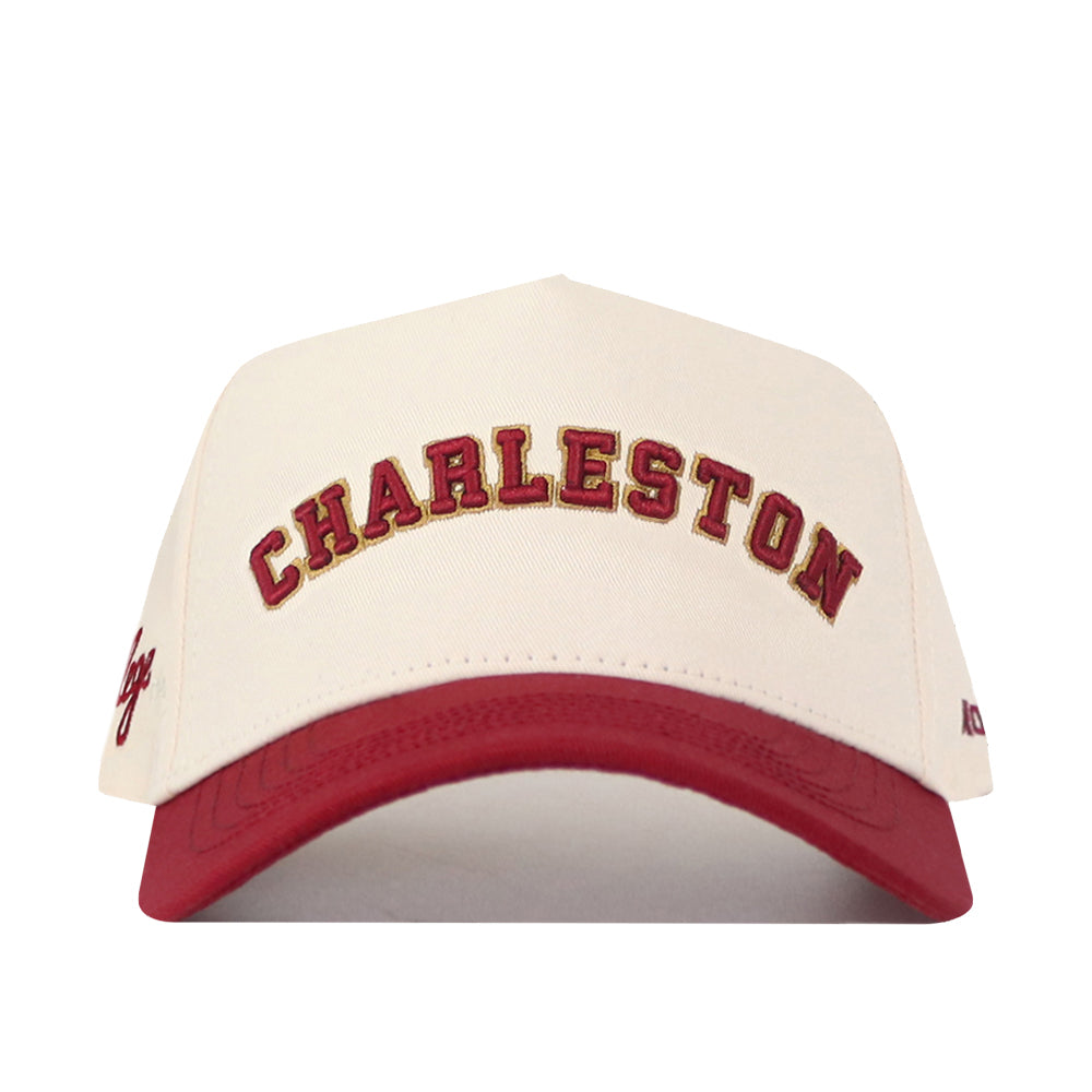 The No Rivals Right Side Up Charleston Hat - Classic is a cream and red baseball cap with "CHARLESTON" embroidered in bold red letters across the front; this officially licensed snapback features striking embroidery for a standout look.