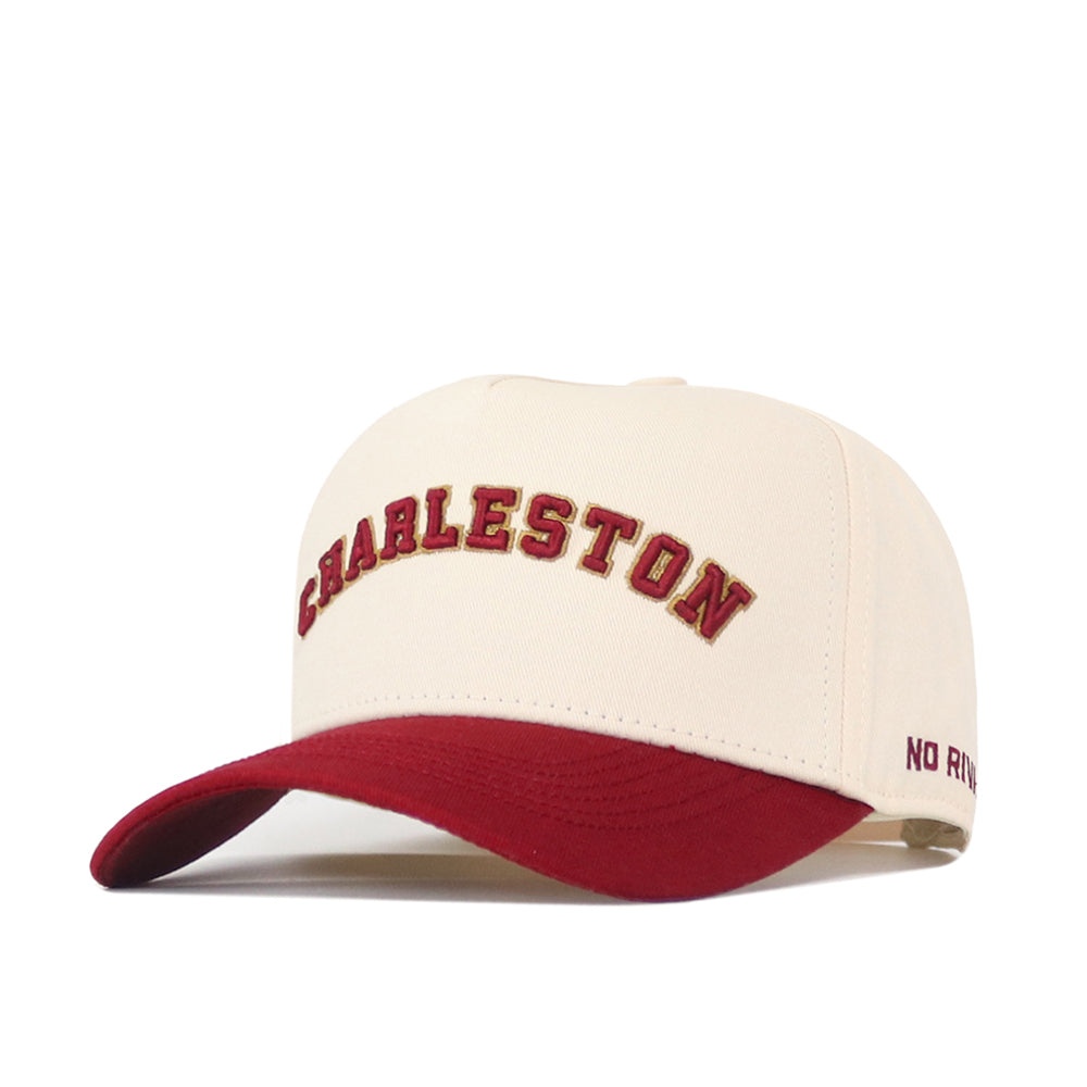 Introducing the Right Side Up Charleston Hat - Classic by No Rivals: This officially licensed snapback features a cream-colored crown with CHARLESTON embroidered in bold red letters on the front and a vibrant red brim. The phrase "NO RIVALS" is stitched in red on the left side of the brim, while an embroidered logo adds the finishing touch to this standout cap.