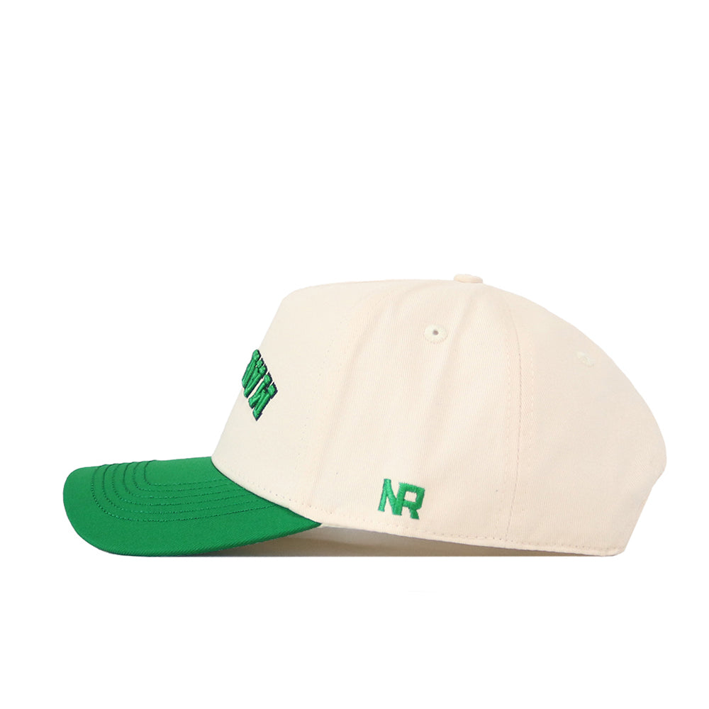 The Upside Down Marshall Hat by No Rivals is a cream-colored six-panel snapback with a green brim, featuring green embroidered "NR" lettering on the side and ventilation eyelets.