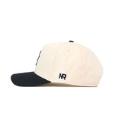 A side view of the App State Logo Patch Hat - Yosef by No Rivals. This cream snapback features a black brim and detailed embroidered logos, including NR initials near the back for added style.