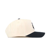 The No Rivals App State Logo Patch Hat - Yosef is a cream-colored baseball cap with a black curved brim and embroidered logos, displayed in side profile against a white background.