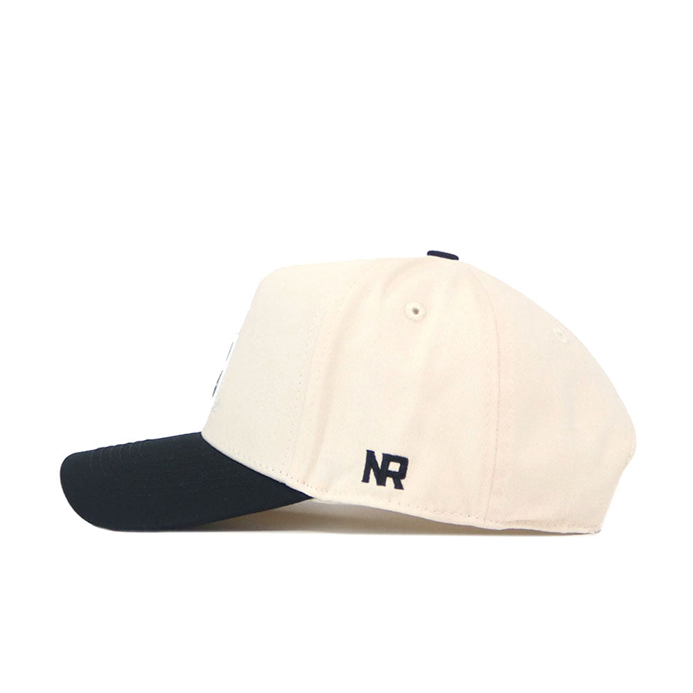 A side view of the App State Logo Patch Hat - Block A by No Rivals shows its beige body, black brim, and distinctive black NR embroidery on the side panel.