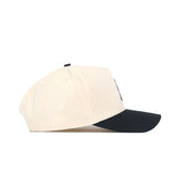 A side view of the No Rivals App State Logo Patch Hat - Block A, an officially licensed snapback with a cream crown and black curved brim, displayed against a plain white background.
