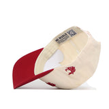 The No Rivals Upside Down Cougars Hat - Washington State is a cream baseball cap with a red brim, shown flipped to display its interior label and QR code. The exterior has an officially licensed embroidered red cougar head logo.