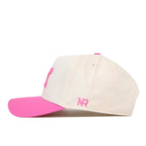 The Michigan Pink Out Hat by No Rivals features a cream-colored crown, a vibrant pink brim, and pink embroidered NR initials on the left side. Designed with a handy snap back closure, this stylish cap is perfect for making a statement and showing your support as a breast cancer awareness hat.