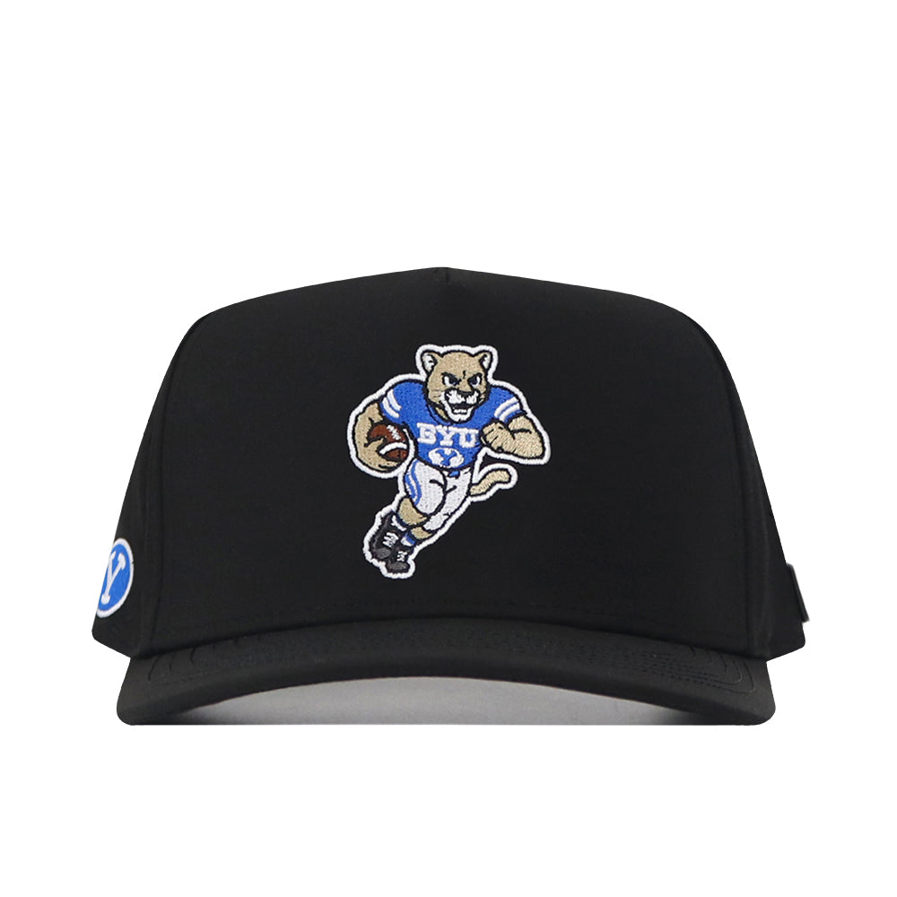 The BYU Cougars Football Mascot Hat by No Rivals features an embroidered cartoon cougar in a BYU jersey holding a football on the front, and a circular BYU logo patch on the left side. This black cap includes a classic snap back closure for adjustable comfort.