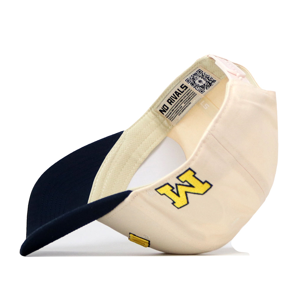 Introducing the Michigan Wolverines | Upside Down Michigan Hat - Classic by No Rivals. This beige baseball cap features a navy blue brim and showcases a yellow embroidered M logo on the side. Made from high quality cotton, it offers an adjustable snapback closure for a comfortable fit. Inside, the label reads “NO RIVALS” and includes a QR code along with size details.