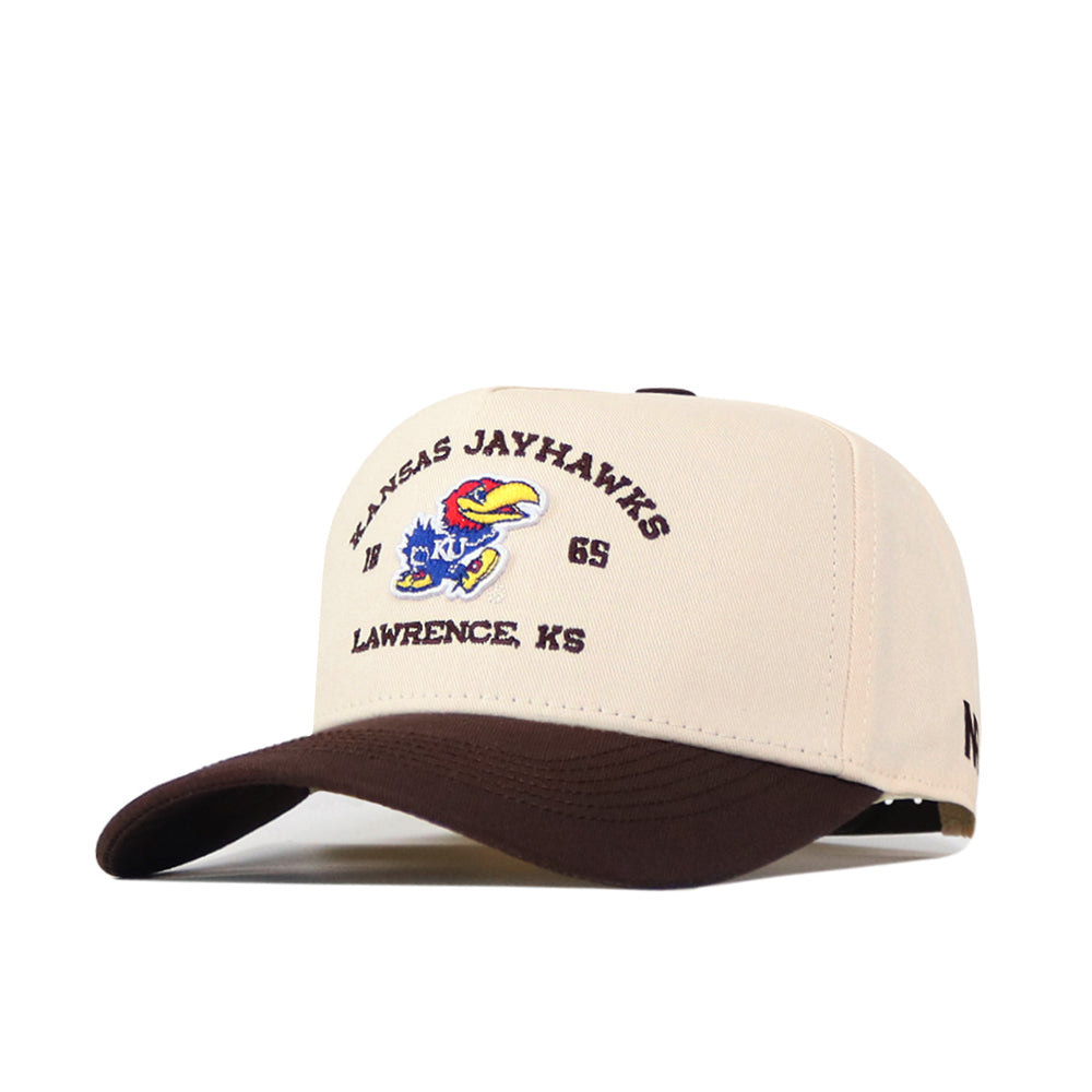 Introducing the Kansas Jayhawks Outlaw Hat - Classic by No Rivals: a beige and brown baseball cap featuring an embroidered Kansas Jayhawks logo, colorful bird mascot, and the text "Kansas Jayhawks, 1965, Lawrence, KS" on the front. Made from high-quality cotton with a comfortable snapback adjustment.