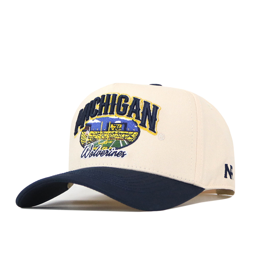 Elevate your ultimate gameday fit with the Michigan Wolverines Stadium Hat by No Rivals—a beige and navy blue baseball cap featuring an embroidered logo, bold text, and a unique train design on the front.