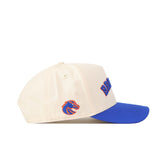 The Right Side Up Broncos Hat - Boise State - Classic by No Rivals is a cream-colored baseball cap with a blue brim, showcasing an officially licensed, embroidered Broncos logo on the front and a bronco head logo on the side. It features an adjustable snap back closure for a comfortable fit.