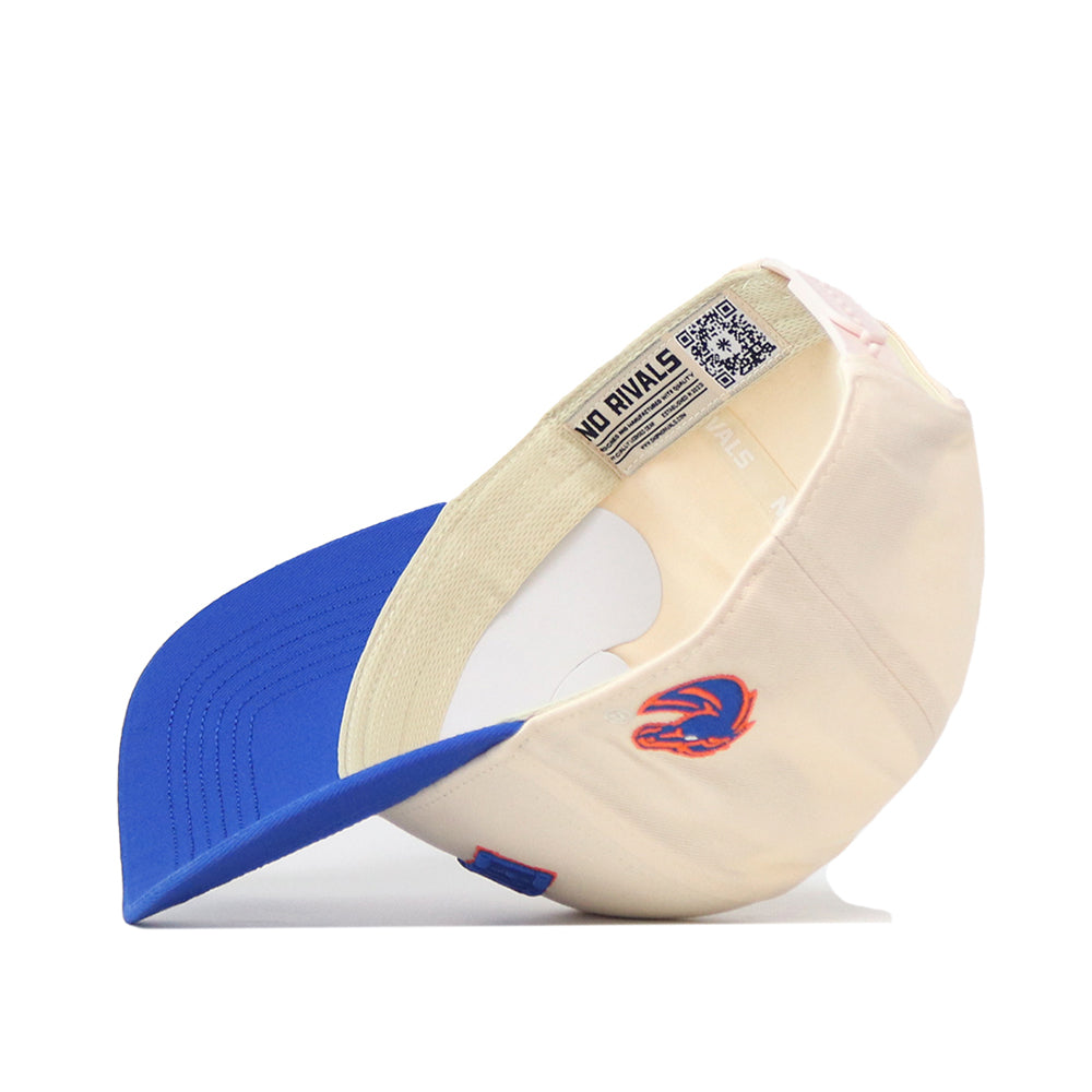 The Right Side Up Broncos Hat - Boise State - Classic by No Rivals is featured in cream and blue, displayed upside down to reveal an embroidered stylized bronco logo on the side and a QR code on the inner tag. This officially licensed snapback is both stylish and functional.