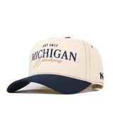 The No Rivals Michigan Wolverines Vintage Hat features a cream top with ventilation holes, a navy brim, and an officially licensed embroidered logo on the front displaying “MICHIGAN” and “Wolverines EST 1817.” This classic baseball cap includes a snap back closure for an adjustable fit.
