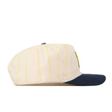 The No Rivals Michigan Wolverines Pinstripe Hat is a cream-colored baseball cap with thin yellow pinstripes and a navy blue brim, featuring a classic snap back adjustment for the perfect gameday fit, shown from the side on a white background.