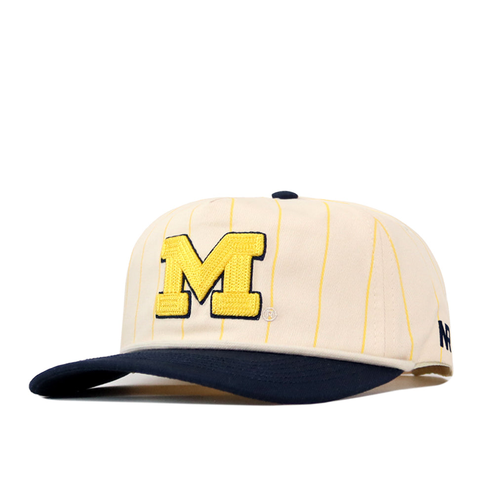 Top off your gameday look with the Michigan Wolverines Pinstripe Hat by No Rivals—a cream cap with thin yellow pinstripes, a bold embroidered yellow M on the front, and a classic navy blue brim. Designed for comfort and style, this timeless piece features a convenient snapback adjustment.