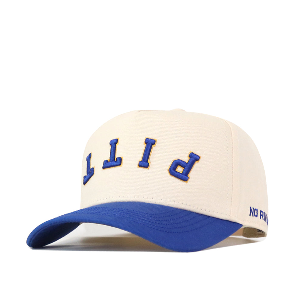 The Pittsburgh Panthers Upside Down Pitt Hat - Classic by No Rivals is a cream-colored snapback baseball cap featuring a blue brim. “PITT” is embroidered upside down in blue and yellow on the front, adding a unique twist, while “NO RING” is stitched in blue on the side of the brim.