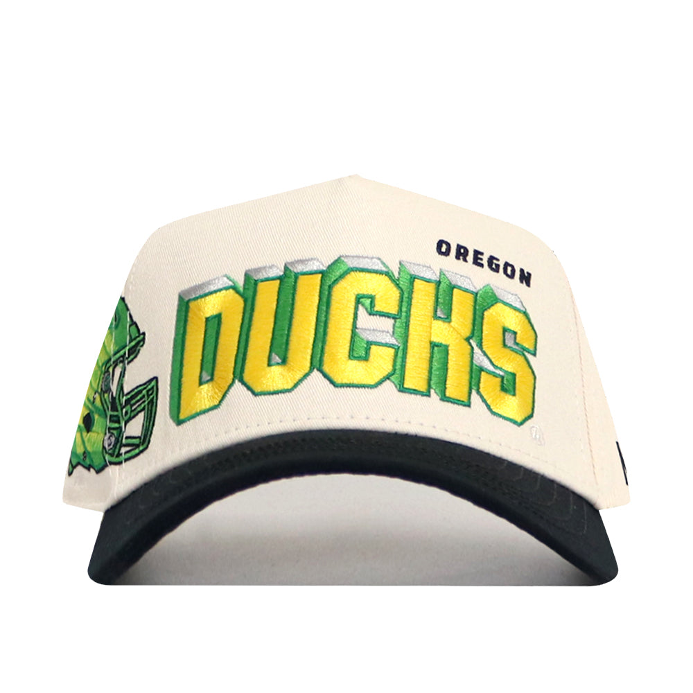 The No Rivals Oregon Alma Mater Hat is a white and black snapback with green and yellow "DUCKS" text, "OREGON" above it, embroidered logos, and a football helmet graphic on the left front.