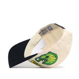 The Oregon Alma Mater Hat by No Rivals features a cream snapback design with a black brim, a green football helmet graphic on the front, an inside label reading NO RIVALS, and a QR code on the inner tag.