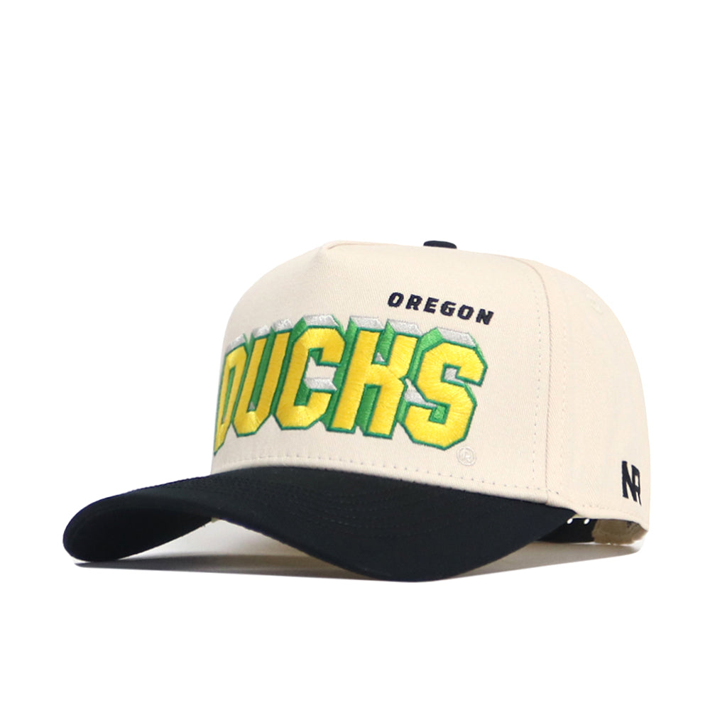 The Oregon Alma Mater Hat by No Rivals is a white and black snapback featuring bold yellow OREGON DUCKS text with green outline embroidered on the front, plus an N logo on the side. This is an officially licensed cap.