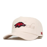 The Arkansas Stacked Hat by No Rivals is a beige snapback crafted from premium cotton with an embroidered red Razorback logo, "Razorbacks" in cursive on the front, and small red N and P on the left side.