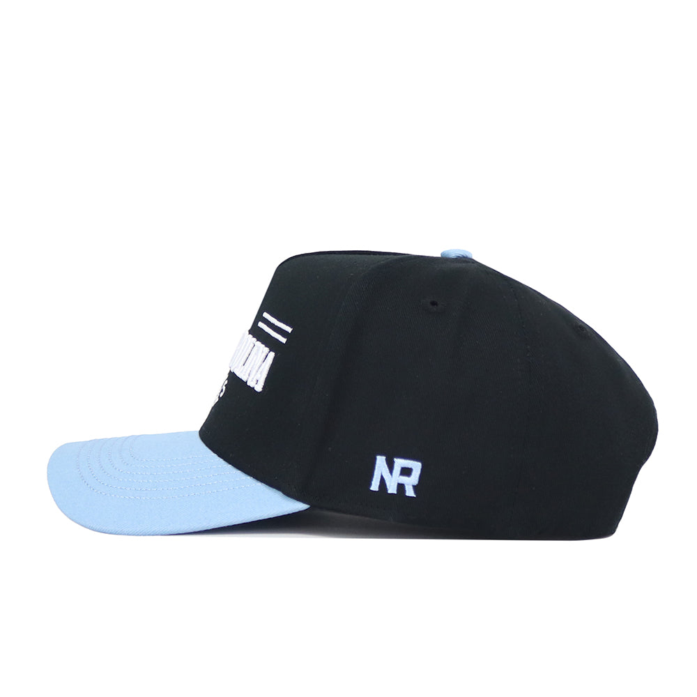The No Rivals North Carolina Tailgate Hat is displayed in a side view. This black structured snapback features a light blue brim, white NR embroidery, and high-quality cotton, set against a plain white background.