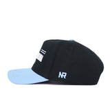 The No Rivals North Carolina Tailgate Hat is displayed in a side view. This black structured snapback features a light blue brim, white NR embroidery, and high-quality cotton, set against a plain white background.