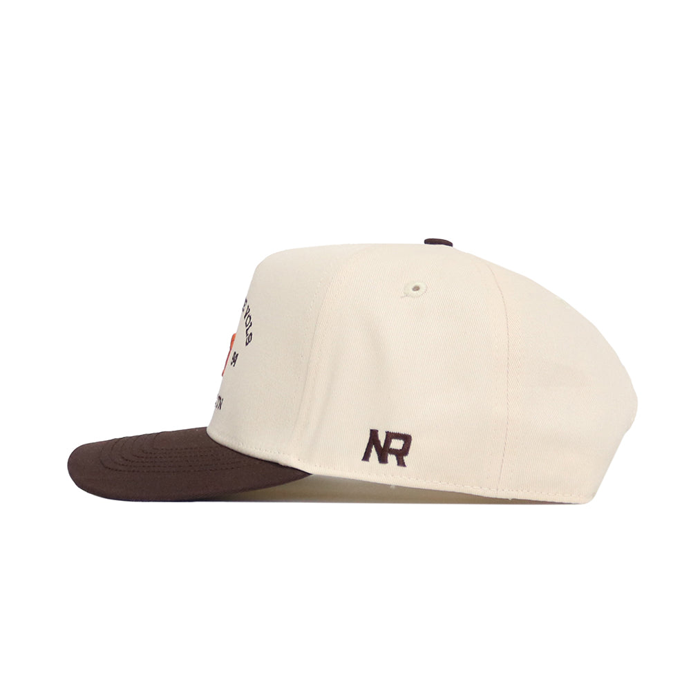The Tennessee Outlaw Hat - Classic by No Rivals is a cream snapback with a brown brim, side view. Made from high-quality cotton, it features small embroidered designs and an NR logo stitched on the side.