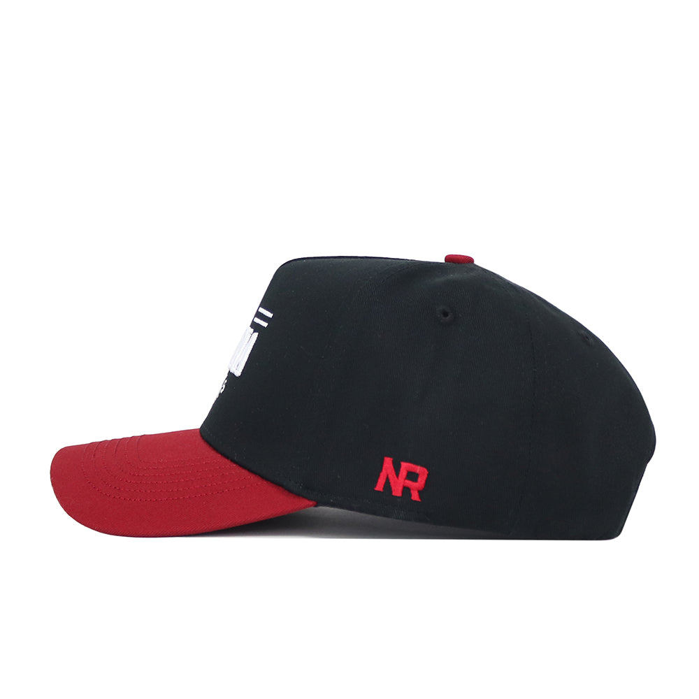 The Indiana Tailgate Hat by No Rivals is a black snapback with a red brim and red NR initials embroidered on the side, made of high-quality cotton for a structured fit, displayed in side view against a white background.