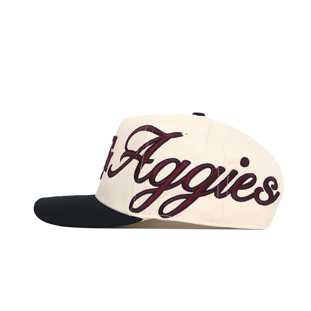 The No Rivals Texas A&M Halftime Hat is a cream-colored cotton baseball cap with a black brim and "Aggies" embroidered in large maroon cursive on the side.