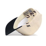 The Texas A&M Halftime Hat by No Rivals is a beige snapback with a black curved brim, high-quality cotton, paisley lining, QR code label, and "NO RIVALS" printed on the inner band. Shown upside down.