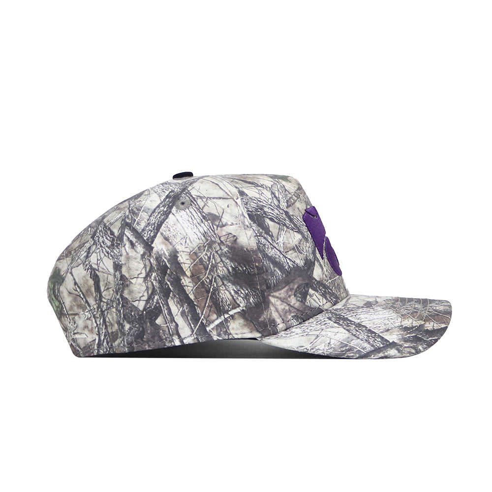 The No Rivals Kansas State Outland Hat is shown in a side view. This structured, cotton snapback features a woodland camouflage pattern, flat brim, and a partially visible purple front logo.