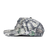 A side view of the South Carolina Outland Hat by No Rivals, a camo print cap with branches and leaves, flat brim, white embroidered NR logo near the back, structured fit, and adjustable snapback.