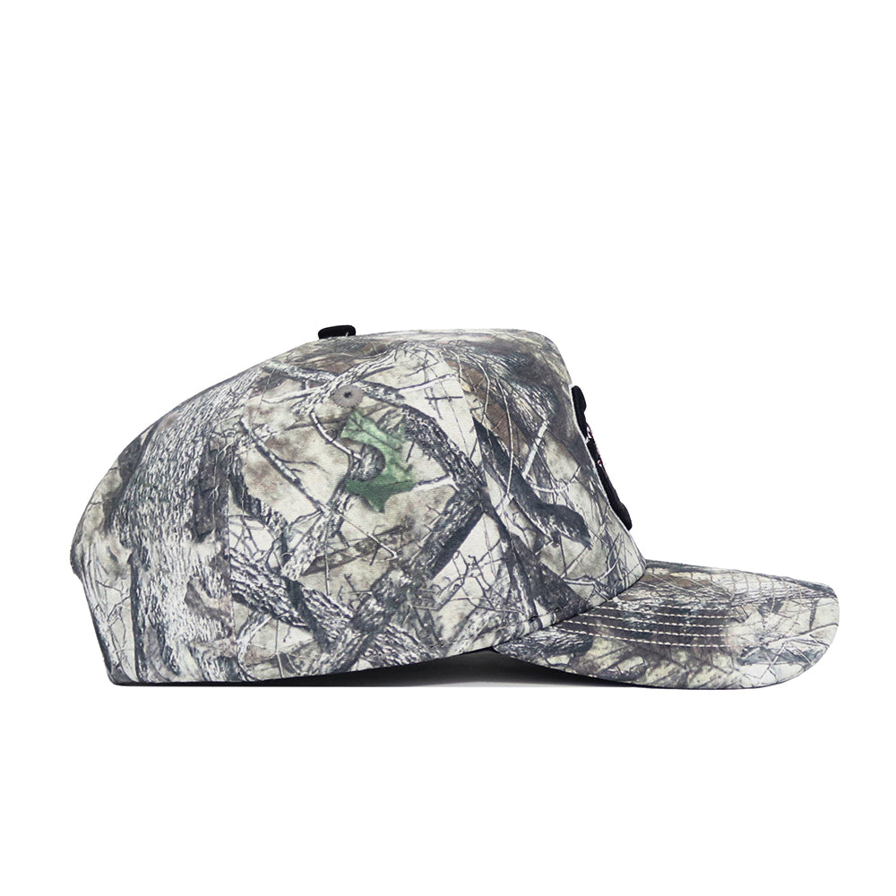 The No Rivals South Carolina Outland Hat is a structured-fit baseball cap with a woodland camouflage pattern in green, brown, and gray. It features a side profile and an adjustable snapback closure for comfort.