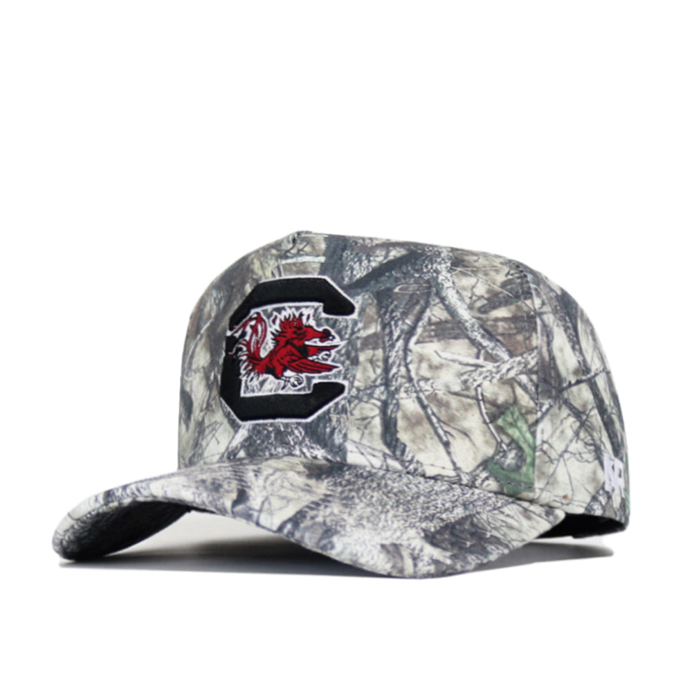 The No Rivals South Carolina Outland Hat features camo print, a large embroidered C with a red gamecock logo on the front, a small white side logo, and a structured fit. Officially licensed for authentic style.