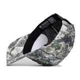 An upside-down Texas A&M Outland Hat by No Rivals reveals its black inner sweatband labeled "NO RIVALS" and a QR code on the rim. This structured snapback, made from high-quality cotton with a camouflage print, sits on a white surface.